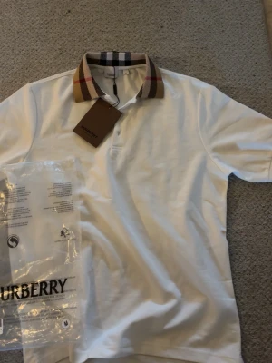 Vit Burberry skjorta med rutig krage - Säljer en vit piké från Burberry eftersom den inte passar mig och har inte använt den alls.