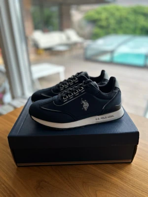 Oanvända U.S Polo 40 Herrskor Blå - Snygga sneakers från United States Polo Association i blå mocka, perfekta inför sommaren. Skorna har aldrig haft en fot i sig, aldrig klivit ett steg, sprillans nya som ni kan se på den andra bilden. De är självklart äkta och kvitto ingår. Antingen kan ni hämta dem i sollentuna eller så kan jag frakta de med köparskydd. Storleken är 40, lite större i storleken. nypris ligger på 1100kr, mitt pris endast 599kr.