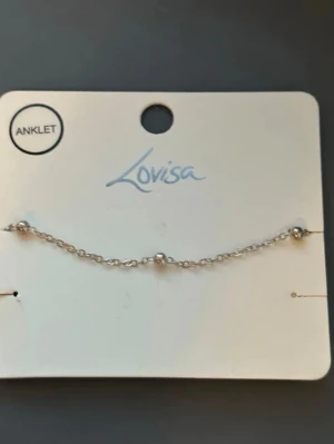 Silverfärgad ankellänk från Lovisa - En tunn ankellänk från Lovisa i silverfärgad metall. Kedjan har små runda detaljer som ger ett minimalistiskt och trendigt intryck. Perfekt accessoar för dig som gillar diskreta men snygga smycken.