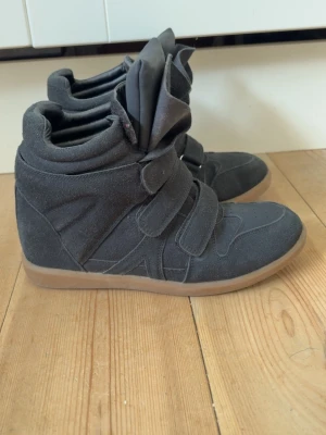 Svarta wedge sneakers - Snygga svarta sneakers med högt skaft och tre breda kardborreband. Dom är från Gina tricot men säljs inte längre. Skorna har en chunky gummisula i beige och är gjorda i mockaliknande material. Plösen är extra vadderad och ger en cool streetwear-vibe. Använda ca 4 gånger så dom är i bra skick.