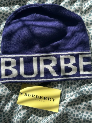 Lila halsduk från Burberry - Snygg lila halsduk från Burberry London England. Tillverkad i ett mjukt tyg som känns lyxigt och har en klassisk rektangulär form. Perfekt accessoar för att lyfta din outfit med en touch av brittisk elegans.