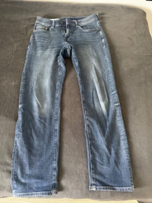 Blå raka jeans - Säljer ett par klassiska blå jeans med raka ben. Jeansen har fem fickor, normal midja och stängs med dragkedja och knapp. Perfekta till en avslappnad stil och passar till det mesta. Materialet är denim