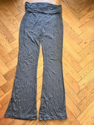 Grå mjukisbyxor  - Säljer ett par grå mjukisbyxor  med bred linning och utsvängda ben. Byxorna är gjorda i ett mjukt och stretchigt material som känns skönt mot huden. Perfekta för chill dagar hemma eller när du vill ha en avslappnad look.