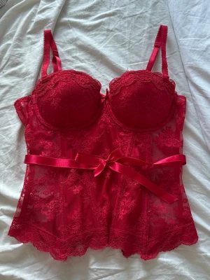 Röd spets korsettopp - Söt korsett topp med knytdetalj! Storlek 38 men sitter tight på mig som bär XS!