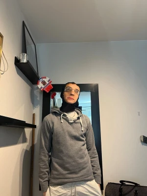 Grå hoodie med vita snören - Säljer en stilren grå hoodie med vita dragsnören i huvan. Hoodien har en klassisk passform och är perfekt för chill dagar. Tillverkad i mjukt material och har ribbade muddar vid ärmslut och nederkant. Enkel att matcha med olika outfits. Modellen är 182 cm väger 75 kg