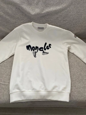 Vit tröja   Moncler - Snygg vit sweatshirt från Moncler med svart tryck. Storlek S. Aldrig använts. 