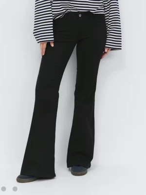 Svarta bootcut jeans med hög midja - Säljer ett par svarta bootcut jeans med hög midja och klassisk femficksdesign. Jeansen har en snygg utsvängd passform som ger en cool siluett. Perfekta att matcha med sneakers eller boots. Materialet är mjukt men inte stretchigt.