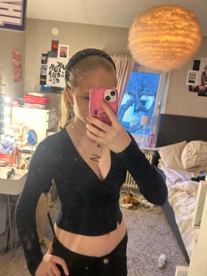 Marinblå omlottopp med v-ringning - Snygg marinblå omlottopp med djup v-ringning och croppad passform. Långärmad modell som sitter tight och framhäver midjan. Perfekt att styla med höga jeans eller kjol för en trendig look. Tror den är ifrån newyorker eller shein💗