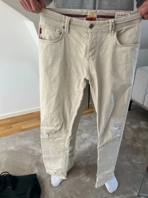 Beiga jeans från Tramarossa - Säljer ett par snygga beiga jeans från Tramarossa, tillverkade i Veneto. Klassisk femficksmodell med bälteshällor och knappgylf. Sköna och stilrena, perfekta till en avslappnad look. Materialet känns mjukt och följsamt.