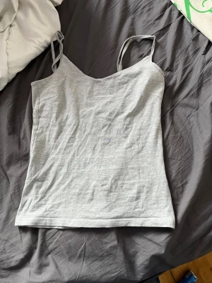 Ljusgrå linnetopp från 157 - Säljer en enkel och stilren ljusgrå linnetopp från 157 med smala axelband. Toppen är gjord i mjuk bomullsblandning med lite stretch för skön passform. Perfekt att matcha med jeans eller kjol för en avslappnad look.