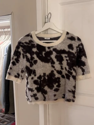 Stickad topp från Kappahl med djurmönster - En supermjuk och fluffig kortärmad tröja från Kappahl med coolt brun-svart och beige djur mönster. Storlek 158-164 men sitter mer som xs-s. Bara använts några enstaka gånger. Tröjan har rund halsringning och är tillverkad i ett lurvigt material som känns riktigt cozy. Skriv vid frågor💕