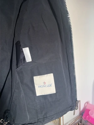 Mörkblå cardiganjacka från Moncler - Snygg mörkblå cardiganjacka från Moncler med rund halsringning och dragkedja framtill. Jackan har fyra fickor med dragkedja och knappar på bröstet och magen. Materialmix med stickade och släta partier ger en cool look. Perfekt för lager-på-lager-stil. Dragkedjan är lite trasig (se bild 2)