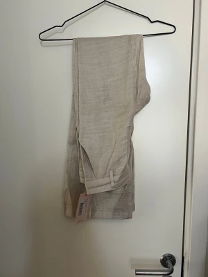Beiga linnebyxor med utsvängda ben - Oanvända kostymbyxor i linnematerial. Slutsålda online och i butik.