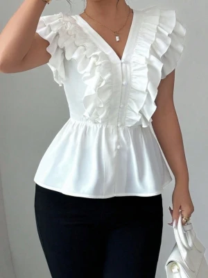Vit volangblus med v-ringning - Snygg vit blus med v-ringning och dekorativa volanger längs axlar och bröst. Blusen är ärmlös och har knappar framtill samt en lätt utsvängd passform. Perfekt för dig som gillar en feminin och trendig stil. Materialet känns lätt och luftigt.