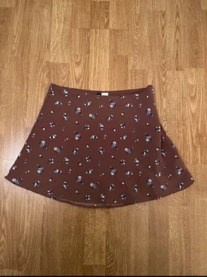 Kjol - Brun kort kjol med blommor från hm i storlek 38 men sitter som en S, mycket fint skick använd 1 gång