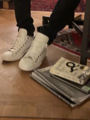 Jimmy Choo skor - Säljer dessa snygga vita high top sneakers från Jimmy Choo. Skorna är tillverkade i läder och har schyssta stjärnor i hälen. Skorna har använts en del vilket syns på färgen, däremot förekommer inga skador på skorna. Jag köpte dem för ett par år sedan och kan inte hitta kvittot. Nypris borde vara runt 5 000 kr.