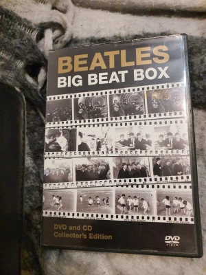 Beatles Big Beat Box DVD och CD - Säljer en Beatles Big Beat Box Collector's Edition med både DVD och CD. Omslaget är svart med guldfärgad text och filmrutor med bilder på Beatles. Perfekt för dig som gillar samlarutgåvor.