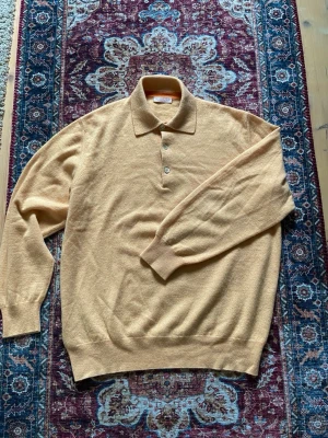 Kaschmir polo - Gul/orange långärmad polotröja i 100% kaschmir. Otroligt fin och mjuk tröja, vilket gör att den knappt känns mot huden. Den perfekta sommartröjan. Storlek 50/M och sitter riktigt bra med en normal passform. 