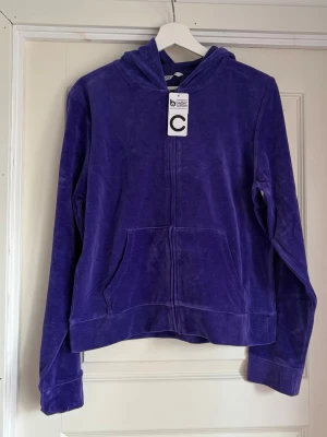 Lila velour hoodie från Cubus - Säljer en lila hoodie i mjuk velour från Cubus. Hoodien har dragkedja framtill, två fickor och en klassisk huva. Perfekt för dig som gillar en chill och bekväm stil. Materialet är lent och ger en skön känsla mot huden.