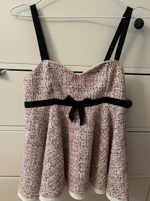 Mönstrad linnetopp från ZARA med rosett - Supersöt linnetopp från ZARA med svart rosett och axelband. Toppen har ett rosa, svart och vitt mönster och en lätt utsvängd form. Perfekt för dig som gillar unika detaljer och trendig stil.