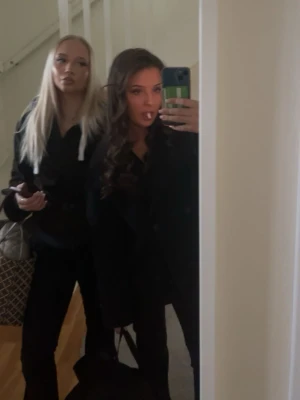 Svart trenchcoat med klassisk krage - Säljer en svart trenchcoat med klassisk krage och knappar framtill. Jackan har långärmad design och en stilren, tidlös look som passar perfekt till olika outfits. Materialet känns mjukt och jackan har en normal passning.