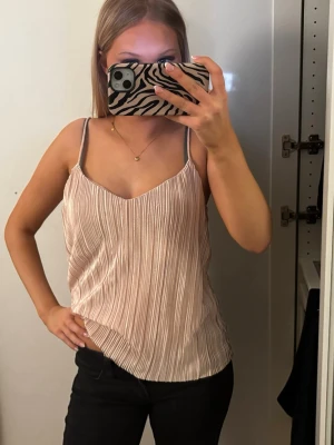 Plisserad ljusrosa linne med smala band - Säljer ett plisserat ljusrosa linne med smala axelband och v-ringning. Fin nu till vår och sommar!💞💞