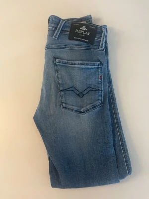Ljusblå jeans från Replay - Snygga ljusblå jeans från Replay med klassisk femficksdesign och broderad bakficka. Jeansen har en avslappnad passform och är tillverkade i mjuk denim med lätt slitning och detaljer. Perfekta för en casual look.
