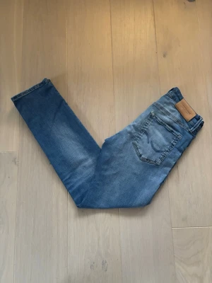 Blå Jack&Jones Jeans - Ett par stilrena jeans från Jack&Jones i färgen blå. Jeansen är i bra skick och rikgt snygg färg. Dem passar till mycket och har en mer slim passform. Storleken är W28 och L30. Pris kan självklart diskuteras!