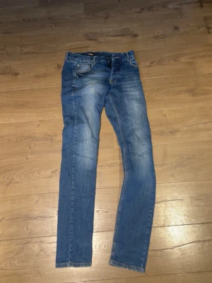 Blå jeans från Solid - Säljer ett par blå jeans från Solid med klassisk femficksdesign och snygga slitningar på framsidan. Jeansen har raka ben och är tillverkade i denim. Perfekta för dig som gillar en avslappnad och trendig look.