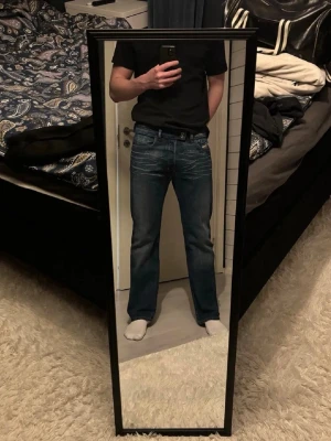 Diesel Straight/Bootcut Jeans - Säljer ett par blå Diesel jeans med Bootcut/Straight passform och snygga slitningar framtill samt under knäveck. Jeansen har klassisk femficksdesign, normal midja och tillverkade i slitstarkt denim. Storlek 31, skulle säga detta motsvarar W32/W33 och L32/33