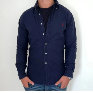 Mörkblå skjorta från Ralph Lauren - Snygg mörkblå skjorta från Ralph Lauren i storlek XS slim fit-modell. Skjortan har långa ärmar, klassisk krage. Säljer nu då jag tyvärr växt ur den. Fortfarande bra skick utan defekter! Skriv privat vid funderingar. 😁
