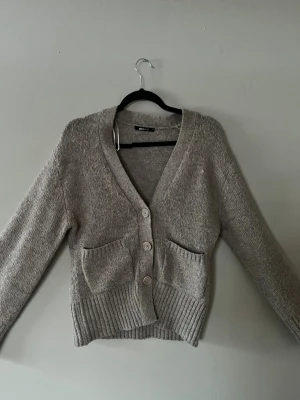 Beige v-ringad stickad kofta med knappar - Snygg beige stickad kofta med v-ringning, knappar och fickor från GinaTricot som passar till allt! Något nopprig men inget jag tänker på!🩷