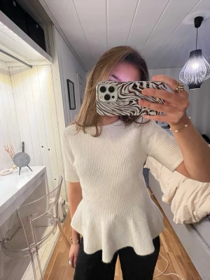 Vit ribbad peplumtop - Säljer en vit ribbad peplumtop med korta ärmar och rund hals. 