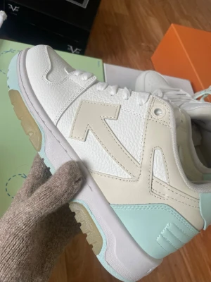 Off-White vita och mintgröna sneakers - Säljer ett par snygga Off-White sneakers i vitt, beige och mintgrönt läder. Skorna har den ikoniska Off-White-pilen på sidan, tjock sula med gummidetaljer och cool retrovibe. Perfekta för dig som vill sticka ut med stilrena detaljer och trendig färgkombo.