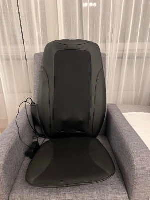 Massage stol  - Elektrisk massagekudde med ryggstöd i svart syntetmaterial och mesh. Kudden har ergonomisk form och är utrustad med sladd och kontroll för enkel användning. Perfekt att lägga på en stol eller fåtölj för extra komfort och avslappning.Nypris 3500