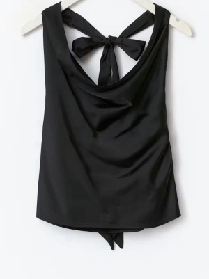 Svart halterneck- silkes topp med öppen rygg och knytning u ryggen  - Toppen är oanvänd med original lappen kvar. Den är i storlek xs ifrån Gina tricot och slutsåld från orginal försäljaren. Det är en svart halterneck silkes topp med öppen rygg.                 Pris går att diskutera 💕