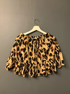 Leopardmönstrad volangkjol - Kort kjol med leopardmönster i beige, svart och bruna toner. Kjolen har volangkant nedtill och resår i midjan för en bekväm passform. 