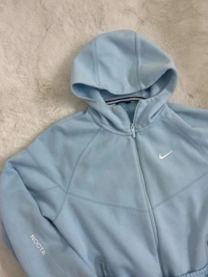 Ljusblå Nike NOCTA mjukis set - Säljer ett  ljusblå set från Nike NOCTA-kollektionen. Byxorna har resår i midjan, sidofickor med dragkedja och en liten vit Nike-logga på benet. Perfekta för chill dagar eller när du vill vara extra bekväm. Den är i använt skick