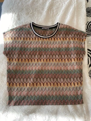 Cool topp Missoni mönster - Kortärmad topp med färgglatt zigzag-mönster i grönt, gult, rosa och brunt. Rund halsringning med vit och svart kant. Köpt på Jakes collection. Hör av er vid frågor!💕