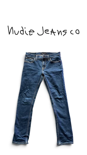 Nudie Jeans Tube Kelly - Snygga Nudie Jeans Tube Kelly i en klassisk mörkblå denim. Stilren modell med en slim och tidlös passform, perfekt till både sneakers och boots.  Jeansen har en snygg naturlig tvätt och fina detaljer som ger dem den klassiska Nudie-känslan.  Storlek: W29 L32 Modell: Tube Kelly Färg: Mörkblå Skick: Mycket fint skick  📦 Skickas välpackade 💬 PM vid frågor eller intresse!