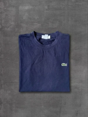 Mörkblå t-shirt från Lacoste - Tja! Säljer denna feta tshirten ifrån Lacoste. Skicket är 9/10, Inga skador osv. Vid frågor kontakta gärna. Storlek S