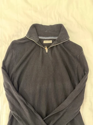 Svart halvzip tröja Jack & Jones - Mörkgrå stickad tröja från Jack & Jones med halvzip och hög krage. Tröjan har långa ärmar och ribbade muddar. Perfekt för lager på lager och enkel att matcha med olika outfits.