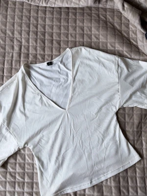 Vit v-ringad topp - Snygg vit croppad topp med v-ringning och korta ärmar. Enkel och stilren design som passar perfekt till jeans eller kjol. Tillverkad i mjukt bomullsmaterial för en bekväm känsla hela dagen. Från SHEIN o aldrig använt. 