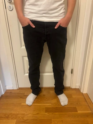 Regular jeans - Säljer ett par svarta jeans med klassisk femficksdesign och normal midja. Jeansen har raka ben och är tillverkade i ett mjukt denimtyg som ger en skön passform. Perfekta för dig som gillar en enkel och stilren look.