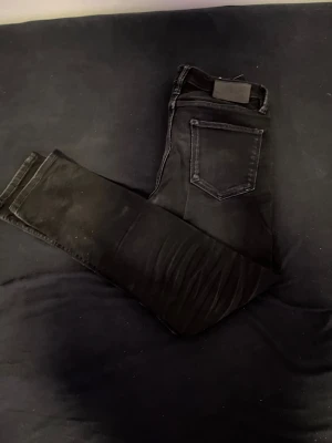 Svarta jeans med stretch - Säljer ett par svarta skinny jeans med hög midja och klassiska fem fickor. Jeansen har en smal passform och är tillverkade i ett stretchigt material för extra komfort. Perfekta till en avslappnad streetstyle-look.