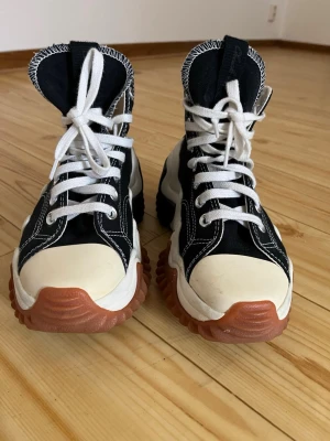 Converse Run Star Motion svart/vit - Säljer ett par Converse Run Star Motion sneakers i svart och vitt med chunky sula i brunt och svart. Skorna har högt skaft, vita snören och den klassiska Converse-loggan på sidan. Materialet är canvas med detaljer i gummi och kontrastsömmar.