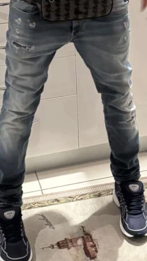 Blå slitna jeans  Replay - Säljer ett par blå jeans från Replay med slitningar och distressed detaljer. Jeansen har smal passform och klassisk femficksdesign. Materialet är denim med en tvättad look som ger en cool och avslappnad stil.