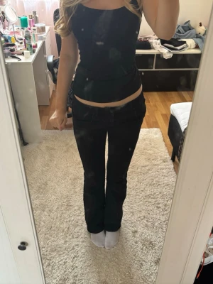 Svarta ltb jeans bootcut - Säljer ett par svarta bootcut jeans med låg midja och klassisk femficksdesign. Jeansen har en tight passform upptill och utsvängda ben. Perfekta för dig som gillar en trendig och stilren look. Jeansen är i storlek 27/32 och passar mig som brukar ha s och är 167