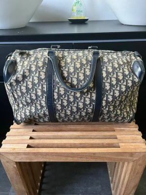 Dior monogram travel bag 20 liter  - Tjena, säljer nu denna riktigt snygga och populära Dior-väska med ett snyggt beige/svart monogram. Väskan är gammal men ändå i bra skick. Finns några små slitage på utsidan av väskan men på insidan är den mycket fin. Alla små slitage visas på bilderna. Mått finns på bilderna: 40 × 22 × 22 cm. Hör av er vid frågor och funderingar🙌🤝 