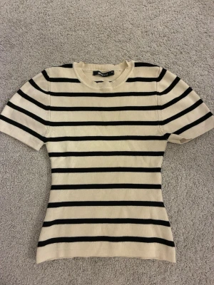 Randig topp från Gina Tricot  - Snygg ribbad topp från Gina Tricot i storlek XS. Toppen är kräm vit med svarta ränder. Säljer då den inte kommer till användning för att jag tycker den är för kort.